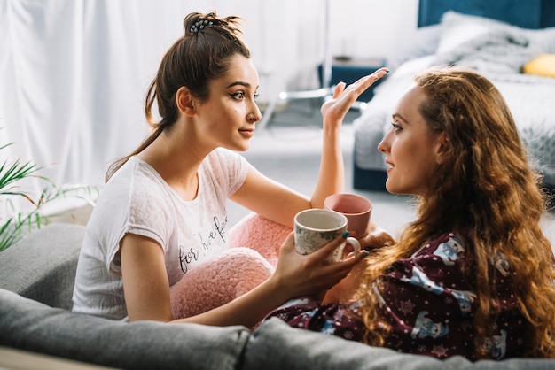 Foto gratuita dos amigas conversando mientras beben café