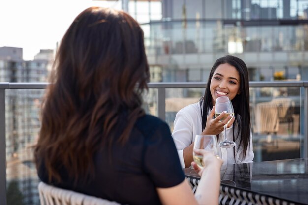 Dos amigas disfrutando de un vino en una terraza en la azotea