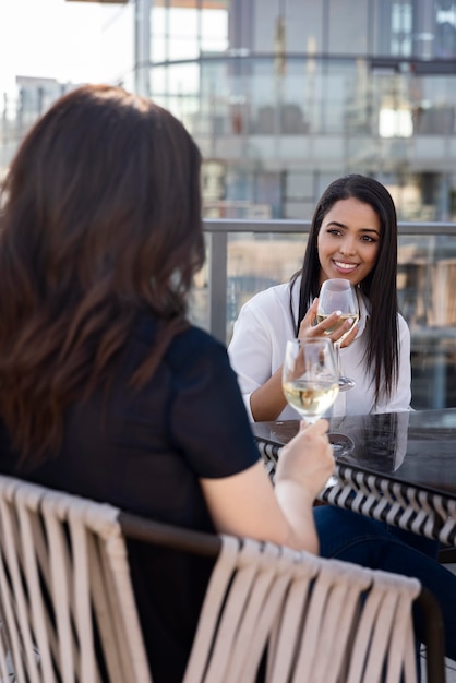 Dos amigas disfrutando de un vino en una terraza en la azotea