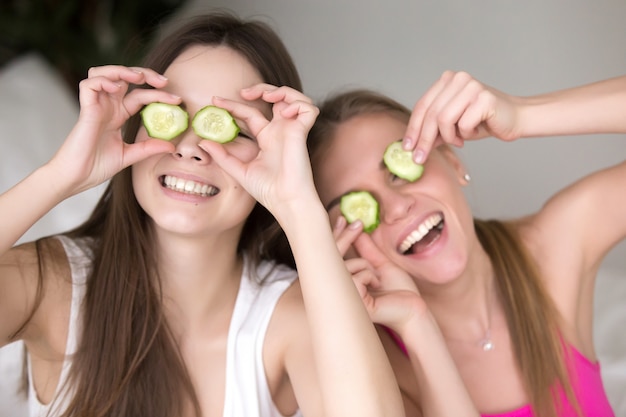 Dos amigas están siendo tontas poniendo pepinos en sus ojos.