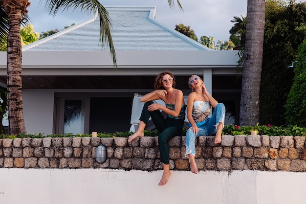 Dos amigas felices con gafas de sol de vacaciones en un país tropical