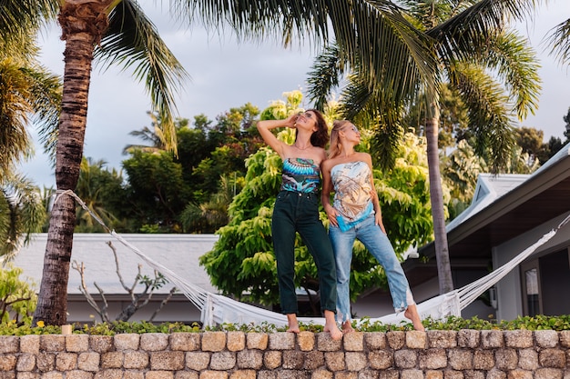 Dos amigas felices con gafas de sol de vacaciones en un país tropical