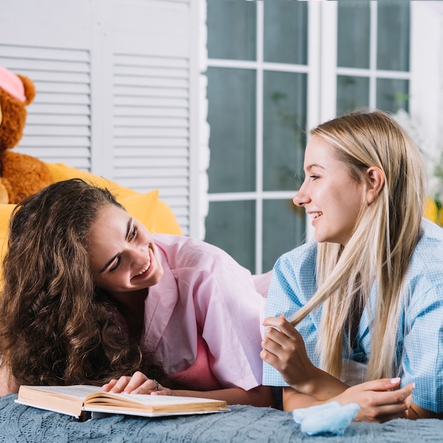 Dos amigas felices con el libro mirando el uno al otro