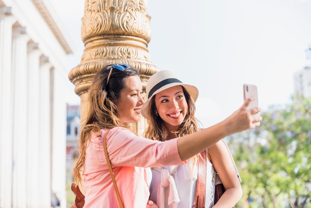 Dos amigas felices que toman autorretrato desde el teléfono móvil