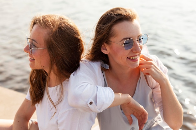 Foto gratuita dos amigas con gafas de sol divirtiéndose junto al lago