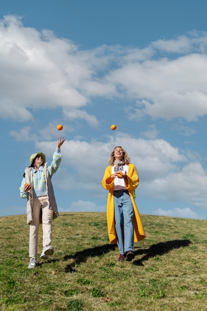 Dos amigas jugando con naranjas en un campo al aire libre