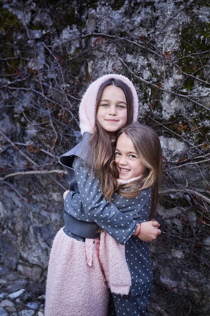 Dos amigas lindas abrazándose entre sí sobre fondo de piedra gris.