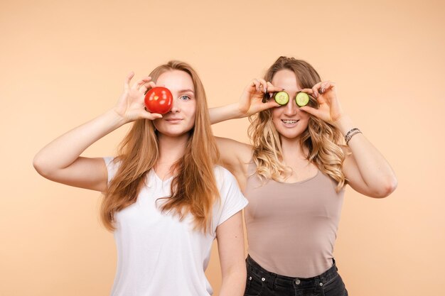 Dos amigas manteniendo tomates y pepinos saludables