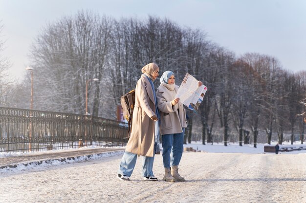 Dos amigas musulmanas consultando un mapa mientras viajan por la ciudad