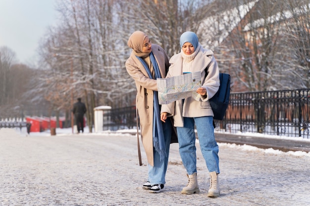 Dos amigas musulmanas consultando un mapa mientras viajan por la ciudad