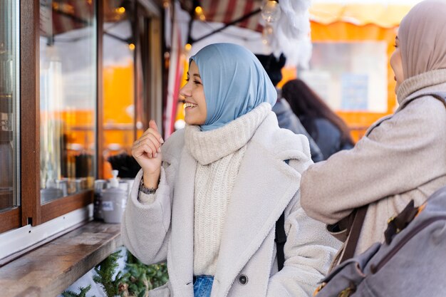 Dos amigas musulmanas sacando un pastel mientras viajan por la ciudad
