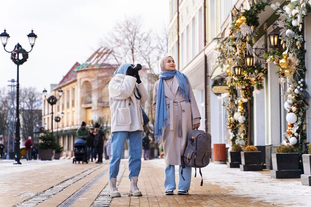 Dos amigas musulmanas tomando fotos de los edificios mientras viajan