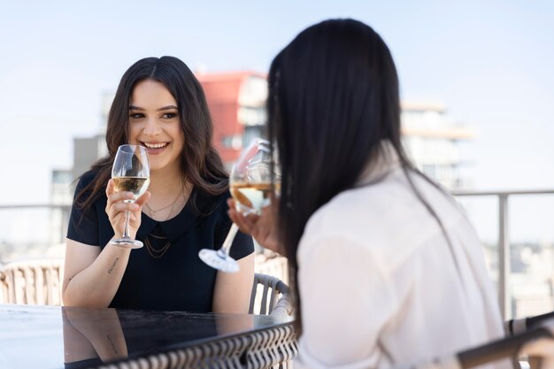 Dos amigas pasar tiempo juntos y beber vino en una terraza en la azotea