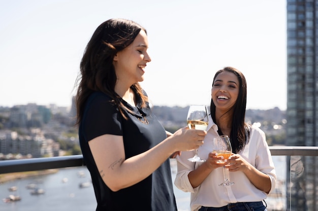 Dos amigas pasar tiempo juntos y beber vino en una terraza en la azotea