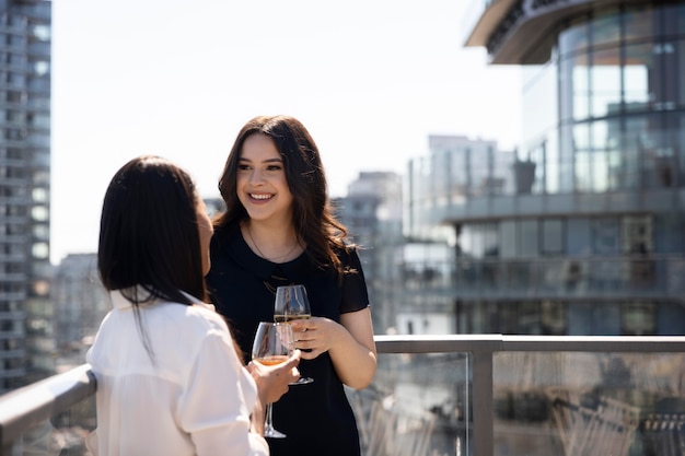 Dos amigas pasar tiempo juntos y beber vino en una terraza en la azotea