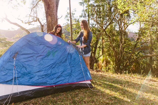 Dos amigas preparando la tienda durante el viaje de campamento