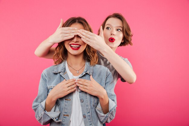 Dos amigas que cubren los ojos con las manos.