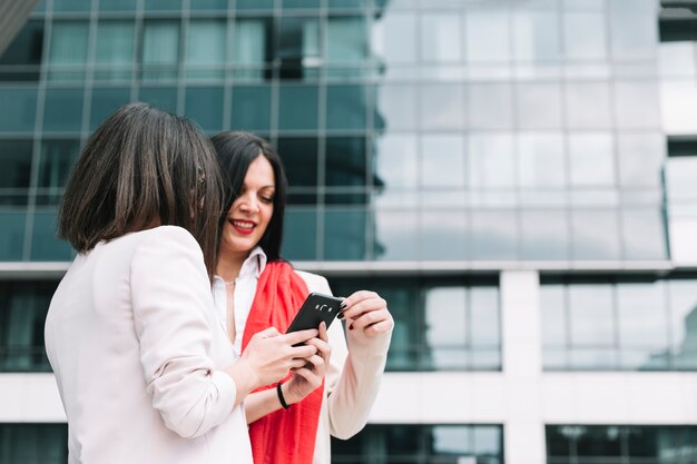 Dos amigas que miran el teléfono móvil con la construcción en el fondo