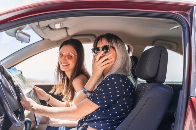 Dos amigas que se sientan en el mapa de la tenencia del coche