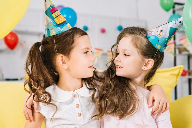 Dos amigas con sombrero de fiesta mirando el uno al otro