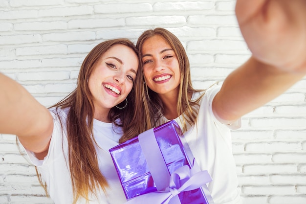 Foto gratuita dos amigas sonrientes con regalo de cumpleaños