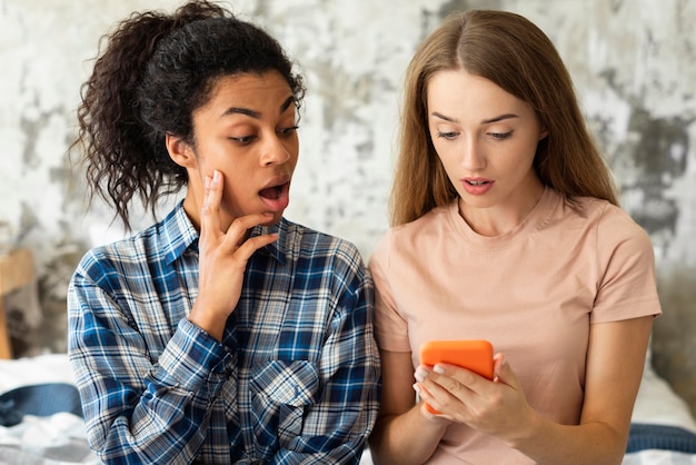 Dos amigas sorprendidas por lo que ven en el teléfono inteligente