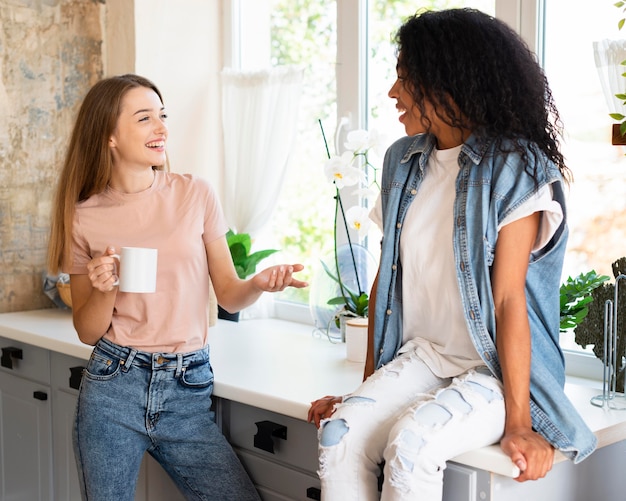 Dos amigas tener una conversación en casa tomando un café