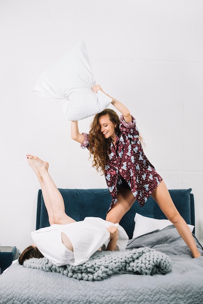 Dos amigas teniendo almohada luchar en el dormitorio