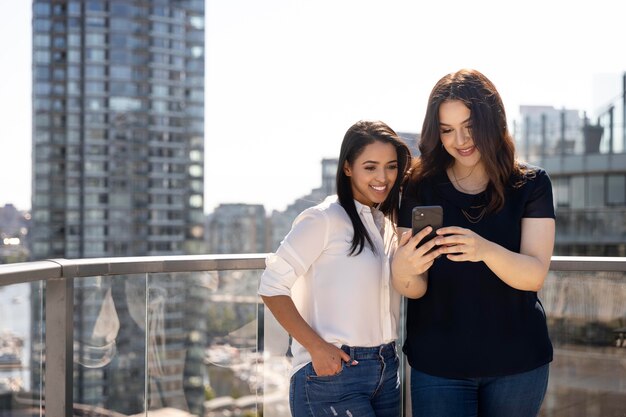 Dos amigas en una terraza en la azotea con smartphone