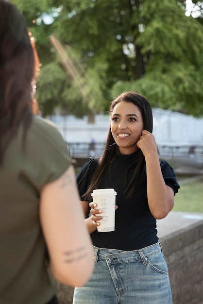 Foto gratuita dos amigas tomando una taza de café juntos en el parque