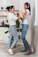 Foto gratuita dos amigos bailando en casa con música en auriculares