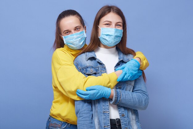 Dos amigos de buen humor, con máscaras y guantes médicos.