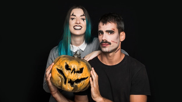 Dos amigos con calabaza espeluznante sobre fondo negro