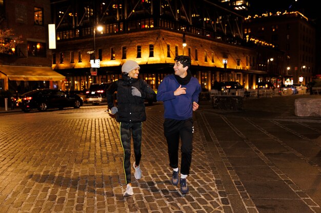 Dos amigos corriendo de noche en la ciudad.