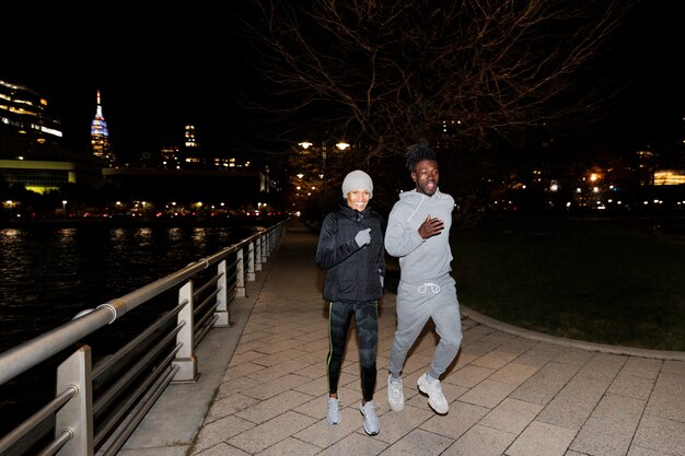 Dos amigos corriendo de noche por un río en la ciudad.