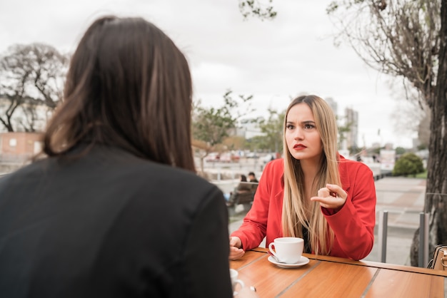 Dos amigos enojados discutiendo mientras está sentado en la cafetería.