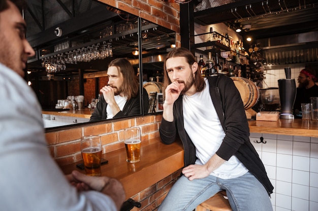 Dos amigos hablando en el bar.