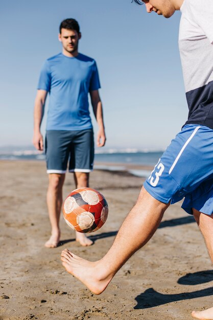 Dos amigos jugando al fútbol en la playa