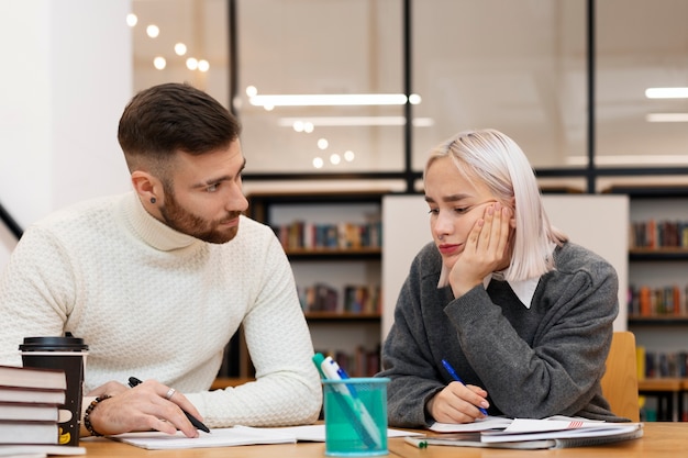 Foto gratuita dos amigos leyendo de un cuaderno durante la sesión de estudio