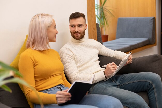 Dos amigos leyendo un libro y un cuaderno en una biblioteca