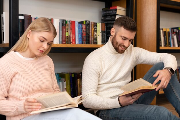 Dos amigos leyendo libros en una biblioteca.