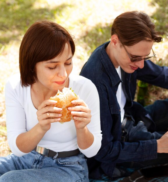 Dos amigos en el parque comiendo hamburguesas