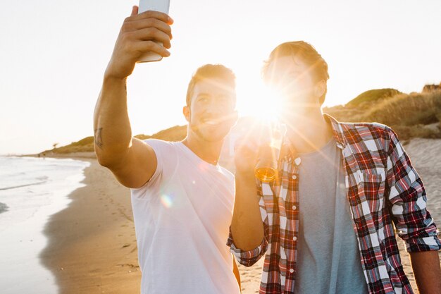 Dos amigos en la playa con puesta de sol