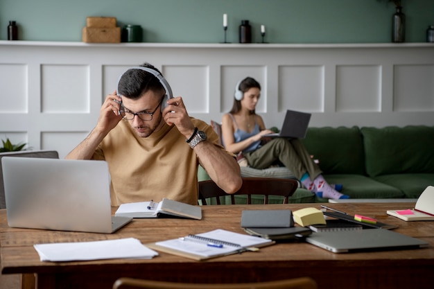 Foto gratuita dos amigos que estudian en una biblioteca usando sus computadoras portátiles