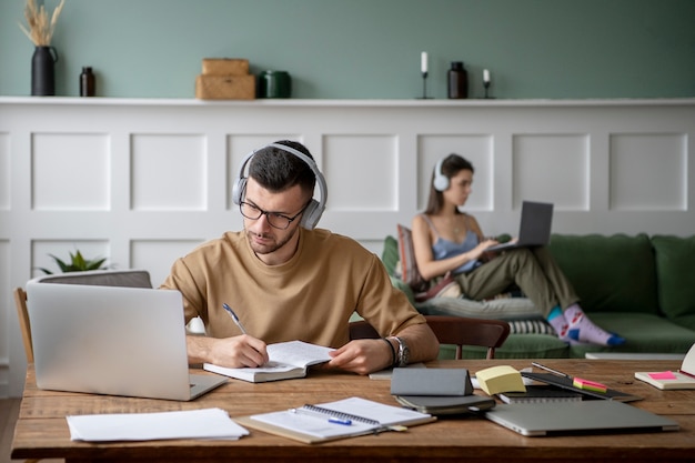 Foto gratuita dos amigos que estudian en una biblioteca usando sus computadoras portátiles