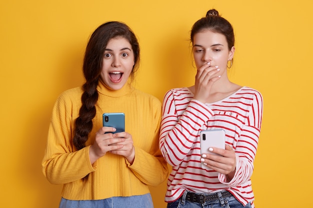 Dos amigos con teléfonos leyendo noticias impactantes en redes sociales