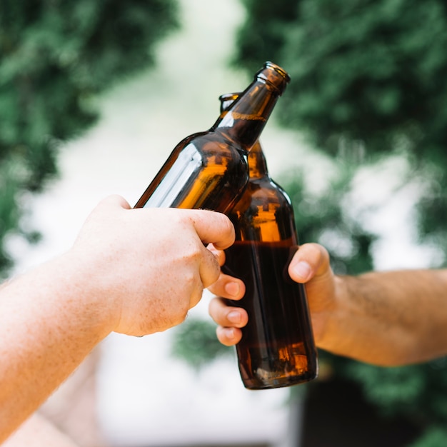 Dos amigos tintinean las botellas de cerveza al aire libre