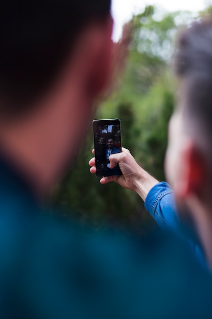 Dos amigos tomando selfie en teléfono inteligente