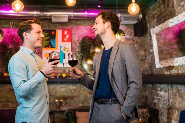 Dos amigos varones felices con vino disfrutando en fiesta