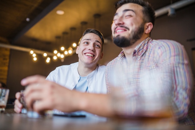 Foto gratuita dos amigos varones sentados a la mesa en el pub